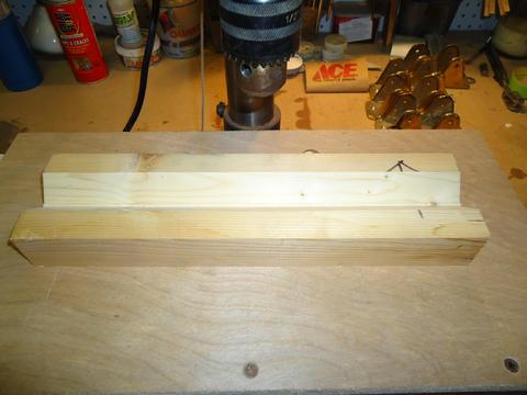 This is a jig cut from a 2x4. I cut two 45 degree bevels to create a 90 degree "trough" to hold round pipe while drilling.