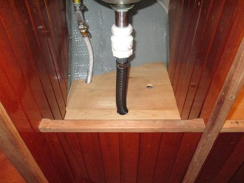 The shelf is split into two parts to fit around the drain line. This aloow quick access to the locker bottom. A finger hole make the self easy to remove.